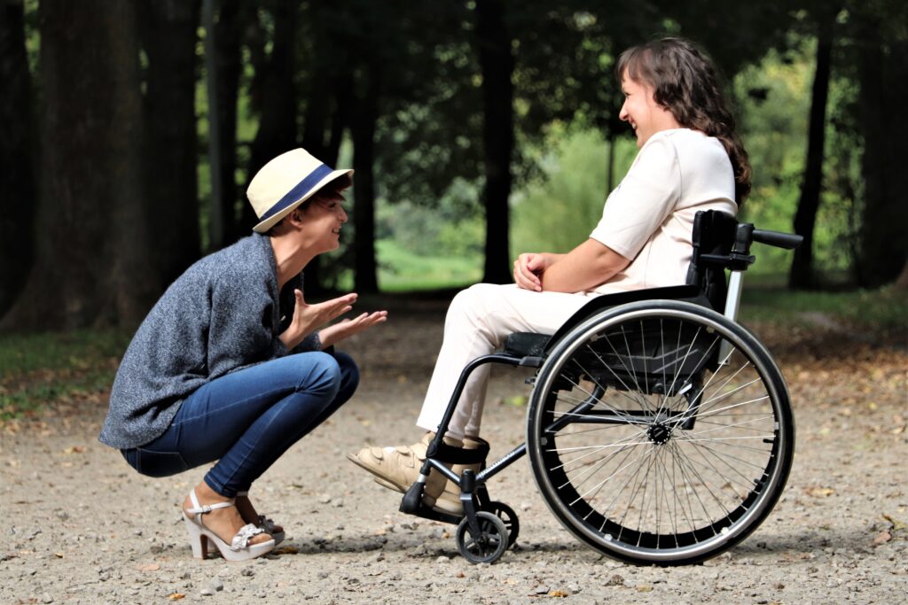 woman in wheelchair talks with woman in heels in park