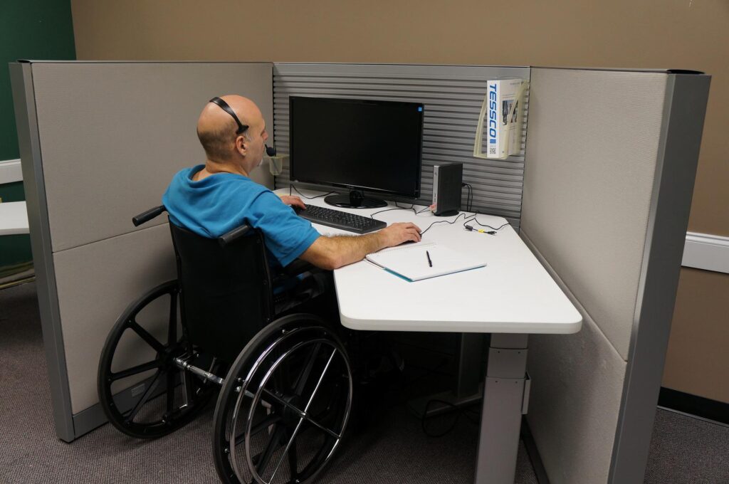 man in wheelchair sitting in front of computer
