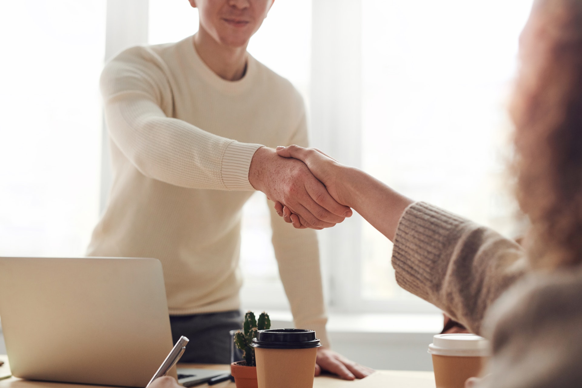 Man shakes hand of job applicant over desk